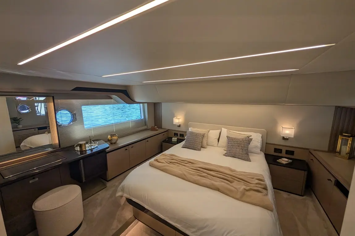 Luxurious yacht bedroom featuring a king-size bed, elegant decor, soft lighting, and a large porthole with ocean view.